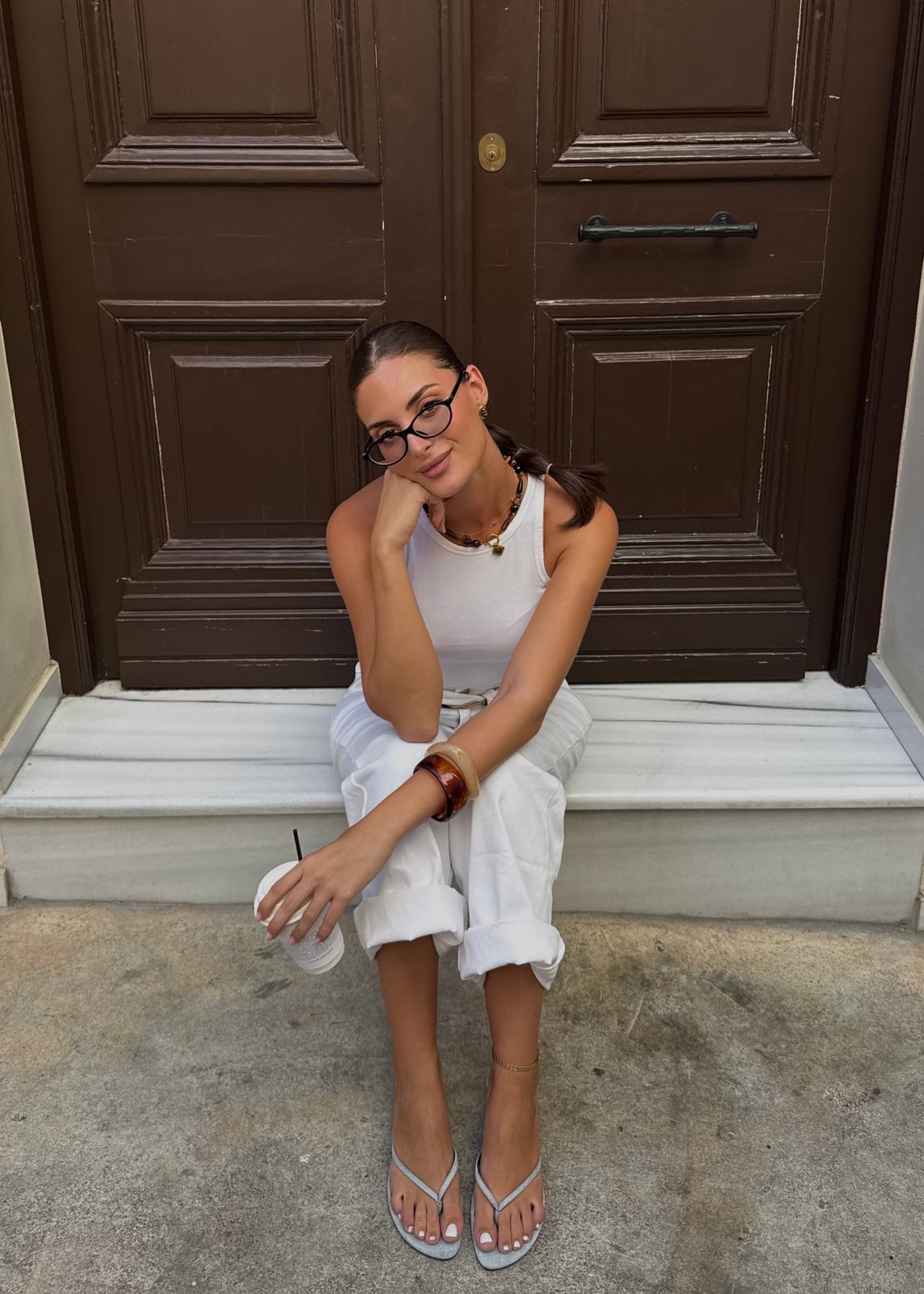 Ada Souropani sitting on a marble doorstep with a coffee